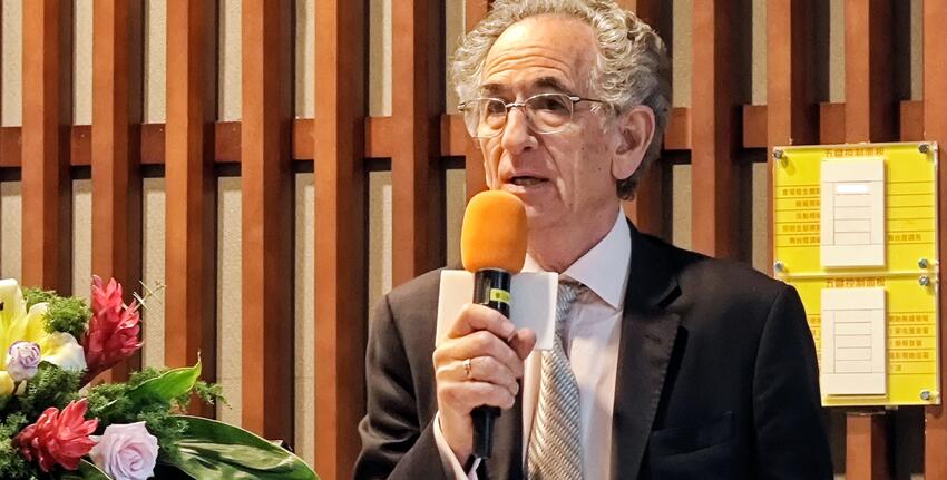 Prof Konvitz speaks into a large orange microphone.